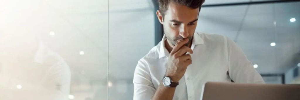 Business professional deep in thought while reviewing information on a laptop.