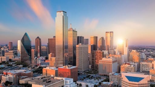 Skyline of a modern city at sunrise, with tall skyscrapers and a clear sky, representing urban development and business growth.