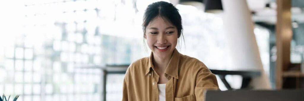 Businesswoman smiling while working on a laptop in a modern office setting