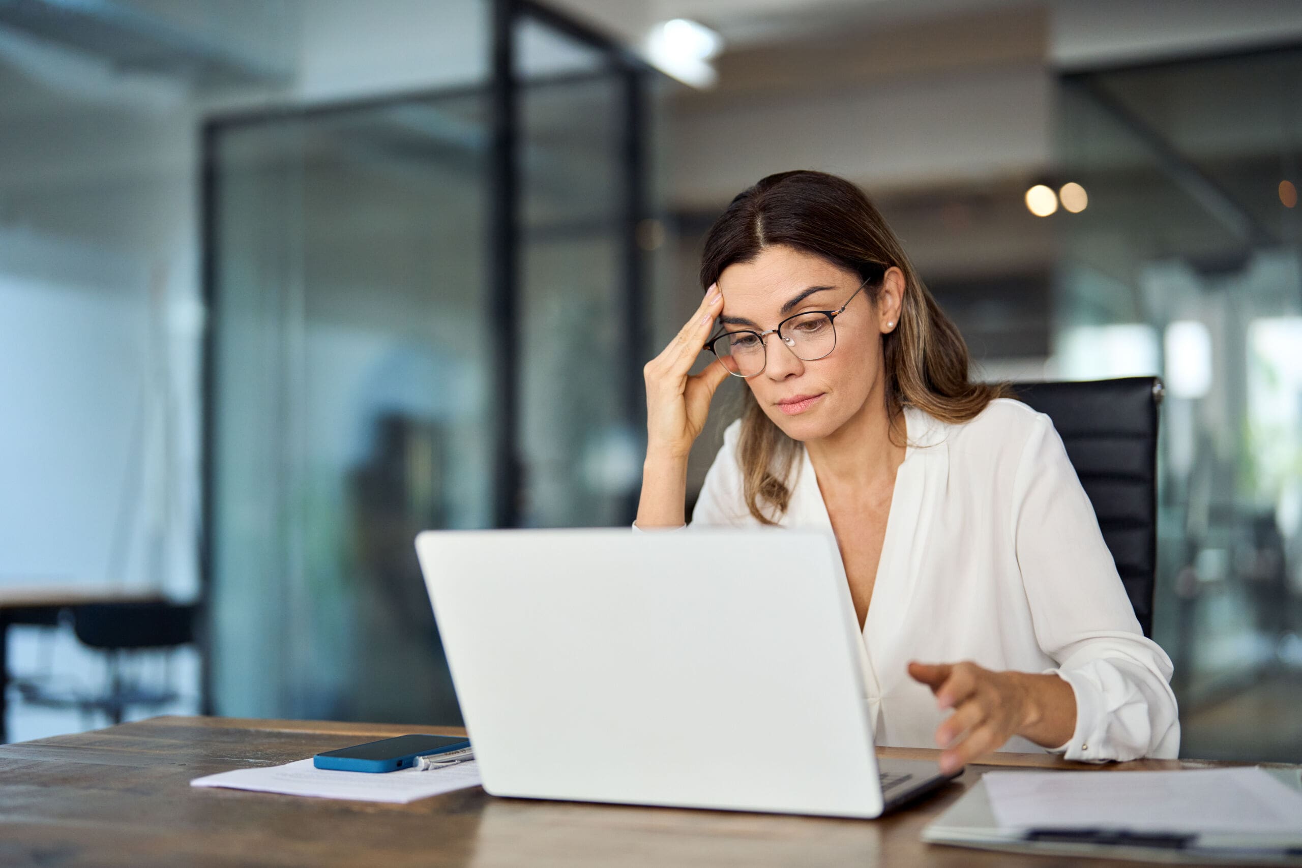 Worried fatigued mature business woman wearing glasses having headache at work. Worried fatigued mature business woman wearing glasses having headache at work. Tired busy 40s middle aged businesswoman feeling stress at workplace looking at laptop computer in office.
